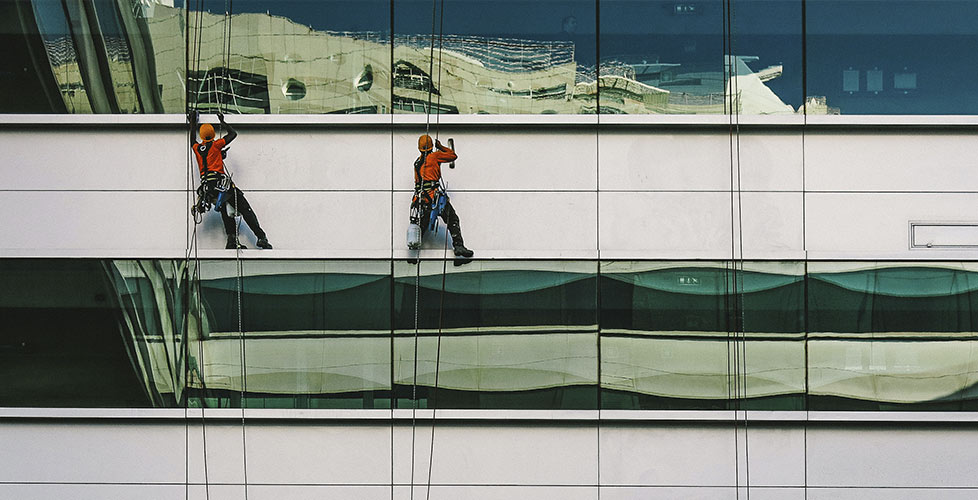 Operarios de reciplac limpiando una fachada acristalada
